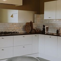 Moderne Kueche eines Ferienhauses in Uffelte, Suedwest-Drenthe, mit weissen Schraenken und sauberer Verarbeitung.