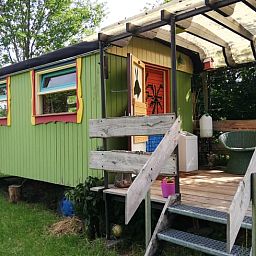 Kleurrijke veranda van vakantiehuis in Elim, Drenthe, met gezellige zitplek en bloempotten.