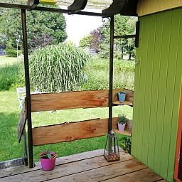 Uitzicht vanaf de veranda van vakantiehuis in Elim, Drenthe, met groene tuin en zonlicht.