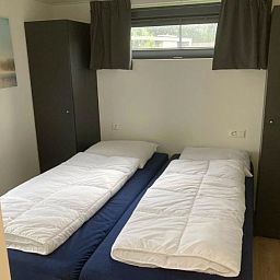 Comfortabele slaapkamer in Vakantiehuis Cube Elite 6, Biddinghuizen, Flevoland met twee eenpersoonsbedden en opbergruimte.