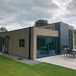 Exterieur van Vakantiehuis Cube Elite 6, Biddinghuizen, Flevoland met terras en ruime tuin omringd door natuur.