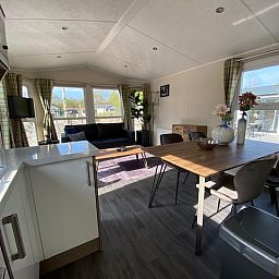 Bright living room of detached house in Biddinghuizen, Eastern Flevoland. Comfortable vacation home with modern furnishings and garden view.