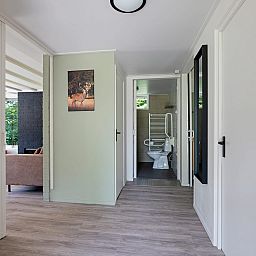 Gang van Aangepaste bungalow de Dobbe in Appelscha, Friese bossen, met toegang tot moderne badkamer en gezellige woonkamer.