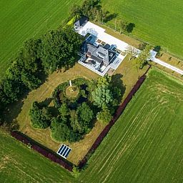 Luchtfoto van vakantiehuisje in Bakkeveen, Friesland, te midden van groene velden.