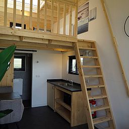 Interior of Chalet in Hindeloopen, Friesland, with wooden interior and stairs to sleeping loft.
