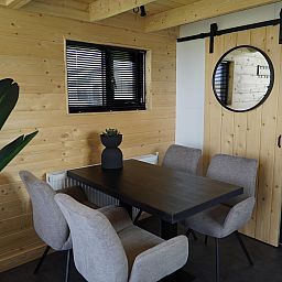 Cozy dining area in Chalet in Hindeloopen, Friesland, with wooden walls and modern furnishings.