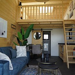 Stylish living room in Chalet in Hindeloopen, Friesland, with comfortable sofa and wooden details.