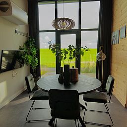 Gemtliches Esszimmer in einem freistehenden Haus in Hindeloopen, Friesland, mit Blick auf grne Felder und moderner Einrichtung.