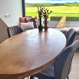 Houten eettafel in Vakantiehuisje in Westhem met panoramisch uitzicht op het Friese platteland, Friesland.