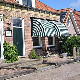 Charmante gevel van Vakantiehuisje in Munnekeburen, Friesland met groene luifel en bakstenen details.