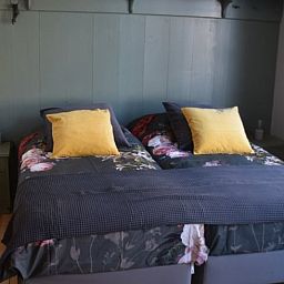 Gezellige slaapkamer in Vakantiehuisje in Munnekeburen, Friesland met comfortabele bedden en kleurrijke kussens.
