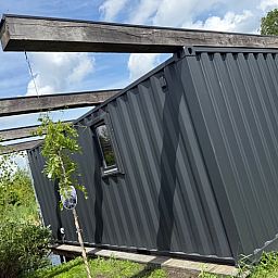 Zijaanzicht van het vakantiehuis in Surhuisterveen te midden van het groene Friese platteland.