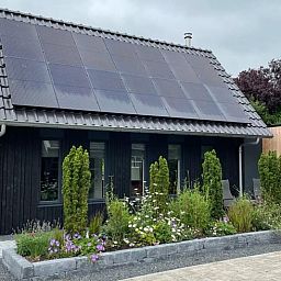 Duurzaam vakantiehuis met zonnepanelen in Bartlehiem, omgeven door tuin op het Friese platteland.
