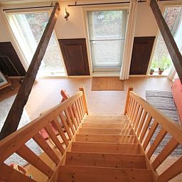 Gezellige binnenruimte van Huisje in Readtsjerk op het Friese platteland, met houten trap en knusse zithoek voor een ontspannen verblijf.