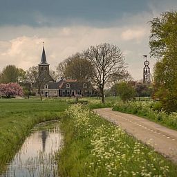 Rustieke omgeving van Huisje in Bears, vakantiehuis op het Friese platteland, met weelderige natuur en serene waterloop in Friesland.