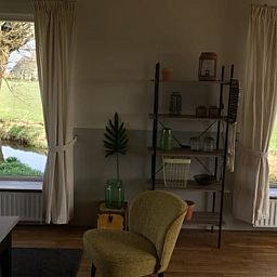 Gemuetliches Wohnzimmer mit Blick auf den Garten im Ferienhaus in Nes, Friesland, ideal zum Entspannen.