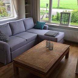 Gemuetliche Sitzecke im Ferienhaus in Nes, Friesland, mit Blick auf die friesische Landschaft.