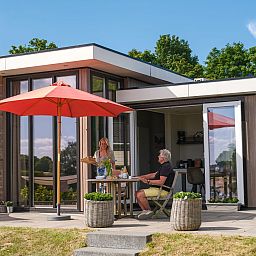 Geniessen Sie die Terrasse von Cube XL mit Sauna, einem modernen Ferienhaus fuer 4 Personen in Lathum, Gelderland, umgeben von Natur.
