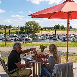 Geniessen Sie das Fruehstueck auf der Terrasse des Cube XL mit Sauna in Lathum, Gelderland, mit Blick auf den Jachthafen und die Natur.