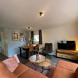 Gemtliches Wohnzimmer in einem freistehenden Haus in Arnheim, Gelderland, mit komfortabler Sitzecke und Esstisch, ideal fr einen entspannten Urlaub.