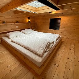 Knusse slaapkamer in Vrijstaande woning in Arnhem, Gelderland, met houten interieur en dakraam voor een rustgevende vakantie-ervaring.