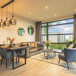 Moderne woonkamer in Vakantiehuis MarinaPark Bad Nederrijn, Maurik, Gelderland, met grote ramen en stijlvolle inrichting.