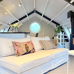 Gezellige binnenruimte van Huisje in Acquoy, vakantiehuis in Rivierengebied, Gelderland, met comfortabele bank en sfeervolle houtkachel.