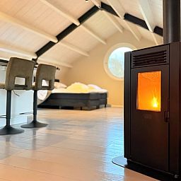 Gezellige binnenruimte van Huisje in Acquoy, vakantiehuis in Rivierengebied, Gelderland, met knusse houtkachel en comfortabele zithoek.