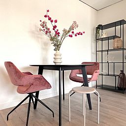 Essecke im Ferienhaus Havenzicht, Maasbommel, mit eleganten rosafarbenen Stuehlen und Blumenschmuck im Rivierengebied, Gelderland.