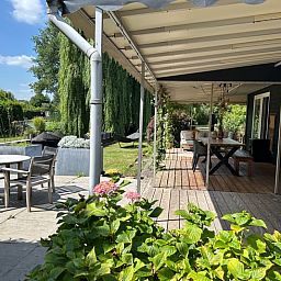 Geniet van de ruime veranda van Huisje in Gellicum, een vakantiehuis in het groene Rivierengebied van Gelderland.