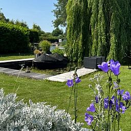 Geniet van de serene tuin van Huisje in Gellicum, vakantiehuis in het Rivierengebied, Gelderland, omgeven door weelderige natuur.