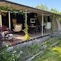 Geniet van de rust op de veranda van Huisje in Gellicum, een charmant vakantiehuis in het groene Rivierengebied, Gelderland.