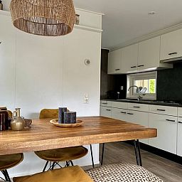 Gezellige keuken en eetruimte in Huisje in Gellicum, vakantiehuis in het Rivierengebied, Gelderland, met een rustieke houten tafel en stijlvolle inrichting.