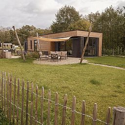 Terras van Parklodge 6 in Kotten, Gelderland: vakantiehuis met moderne zitplaatsen en groen.