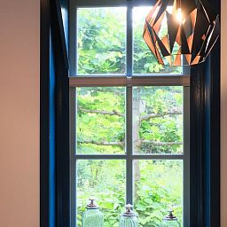 Gemuetlicher Innenbereich des Ferienhauses in Zelhem, Achterhoek, mit Blick auf die gruene Natur durch ein schoenes Fenster.