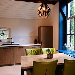 Moderne Kueche im Ferienhaus in Zelhem, Achterhoek, Gelderland mit Holzinterieur und Blick auf die gruene Umgebung.