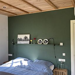 Cozy bedroom in Huisje in Westendorp, bed and breakfast in the Achterhoek, with wooden ceiling and soothing green walls.