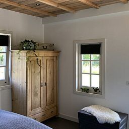 Bright room at Huisje in Westendorp, bed and breakfast in Gelderland, with wooden wardrobe and garden views.