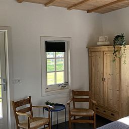 Cozy sitting area in Huisje in Westendorp, bed and breakfast in the Achterhoek, with wooden chairs and views of greenery.