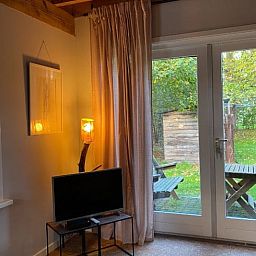 Gemuetliches Wohnzimmer von Cottage in Laren (gld), Ferienhaus in Achterhoek, Gelderland, mit Blick auf gruenen Garten und Terrasse.