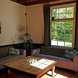 Cozy living room in Holiday Home in Vorden, Achterhoek, Gelderland with comfortable sofas and views of green nature.