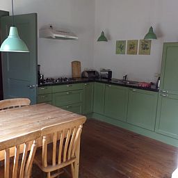 Cozy kitchen in Cottage in Vorden, Achterhoek, Gelderland with wooden dining table and green cabinets for a homely stay.