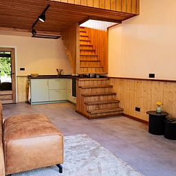 Gezellige woonkamer in Vakantiehuisje in Neede, Achterhoek, met moderne keuken en houten trap.