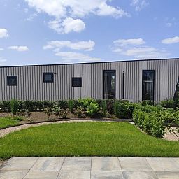 Detached house in Olburgen, Achterhoek: modern vacation home with green garden and clear blue sky in Gelderland.
