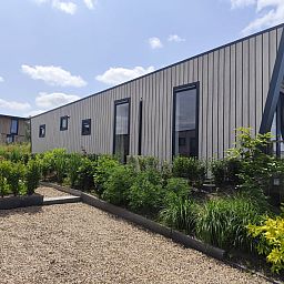Detached house in Olburgen, Achterhoek, Gelderland, surrounded by green garden and blue sky, ideal vacation home for peace seekers.