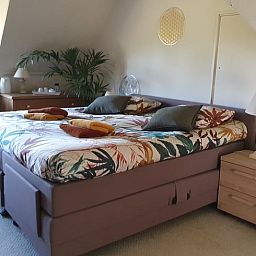 Cozy bedroom in Cottage in Warnsveld, Achterhoek, with colorful blankets and bedside tables.