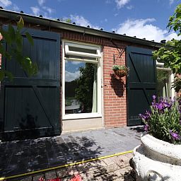 Authentieke gevel van Vakantiehuisje in Winterswijk Woold, omringd door kleurrijke bloemen in de serene Achterhoek, Gelderland.