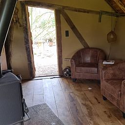 Holzofen und bequeme Stuehle im Ferienhaus in Winterswijk Corle, Achterhoek.