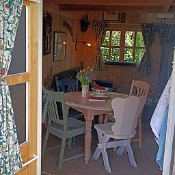 Gemuetliches Interieur des Ferienhauses in Winterswijk Corle mit Holzinterieur und farbenfrohen Stuehlen, gelegen in Achterhoek, Gelderland.