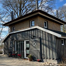 Charmant exterieur van Huisje in Empe, vakantieverblijf in Gelderland, omgeven door bomen.
